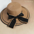Beige straw hat with a black ribbon on a beige background, branded 'SparkleSway'.