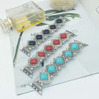 Bracelets with colorful gemstones on a magazine page with a perfume bottle.