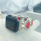 Smartwatch with a decorative band featuring red gemstones and silver accents on a light background.