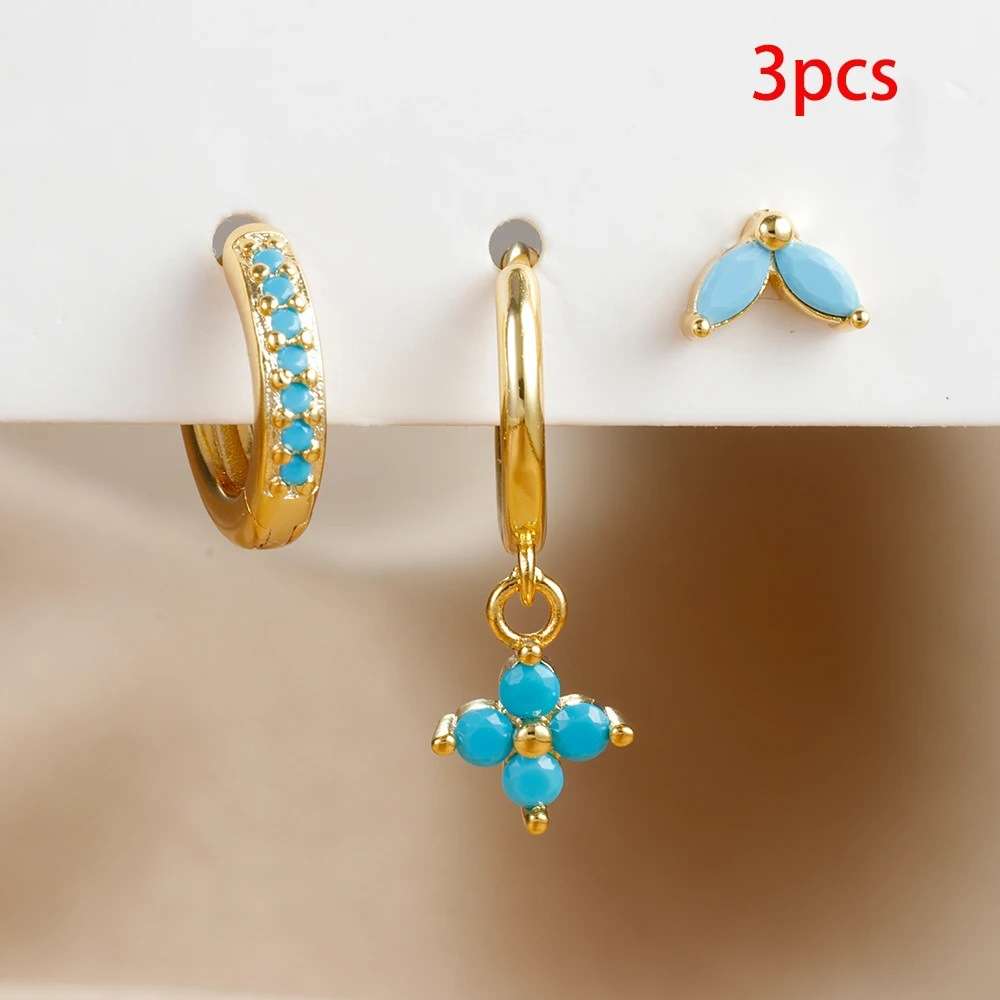 Gold hoop earrings with turquoise stones on a beige background