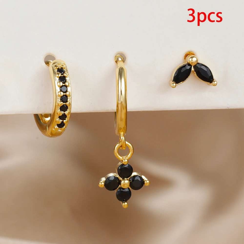 Three-piece gold huggie hoop and stud earring set with black gemstone accents, displayed on a white stand against a beige satin background with a red '3pcs' text overlay.