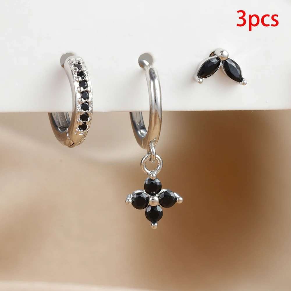 Three pairs of silver hoop and stud earrings with black gemstones, displayed on a white stand against a beige background. A red text overlay in the top right corner reads '3pcs'.