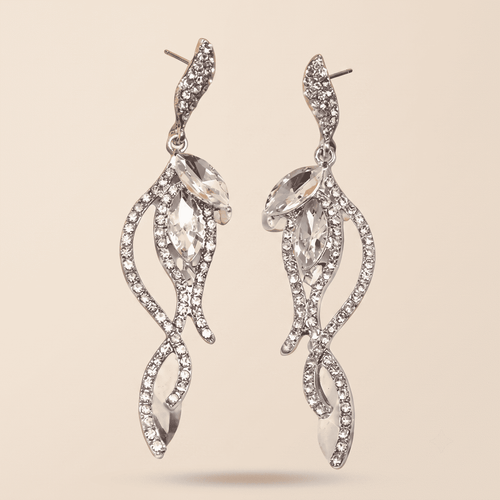 A pair of silver-toned dangle earrings with marquise-cut clear crystals and pavé-set rhinestones in a swirling leaf-like design, shown on a solid beige background.
