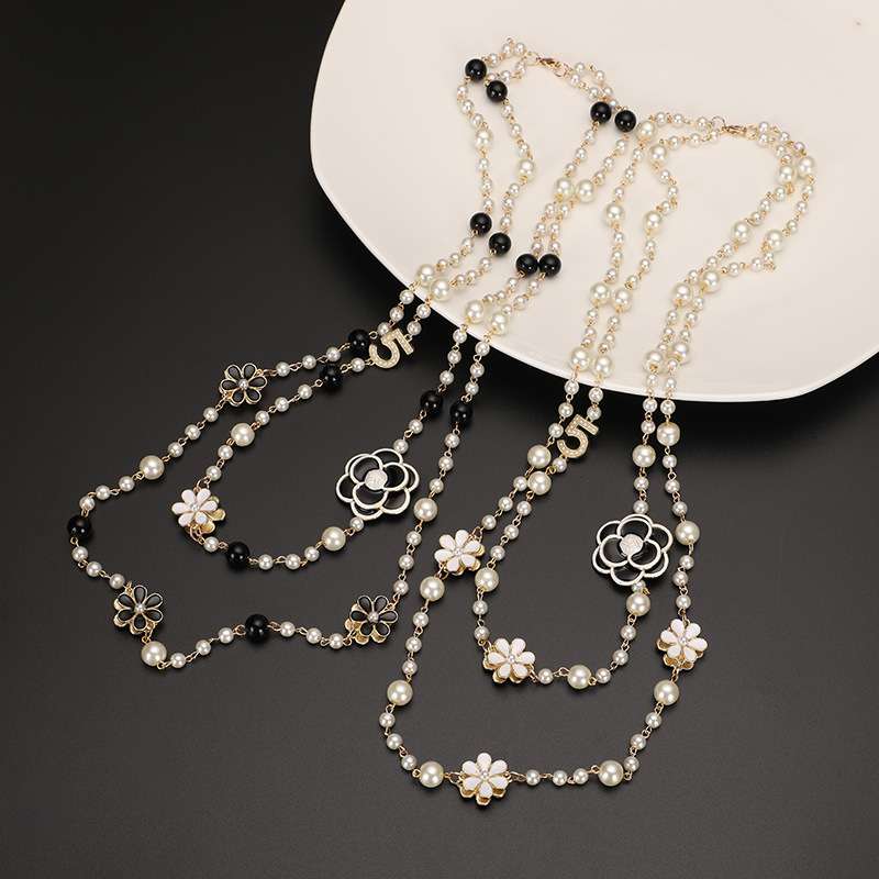 Pearl necklace with floral designs on a dark surface