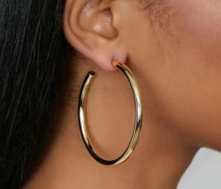 Gold hoop earring worn by a person with dark hair.