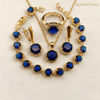 Jewelry set with blue stones on a light beige background, featuring the brand 'SparkleSway'.