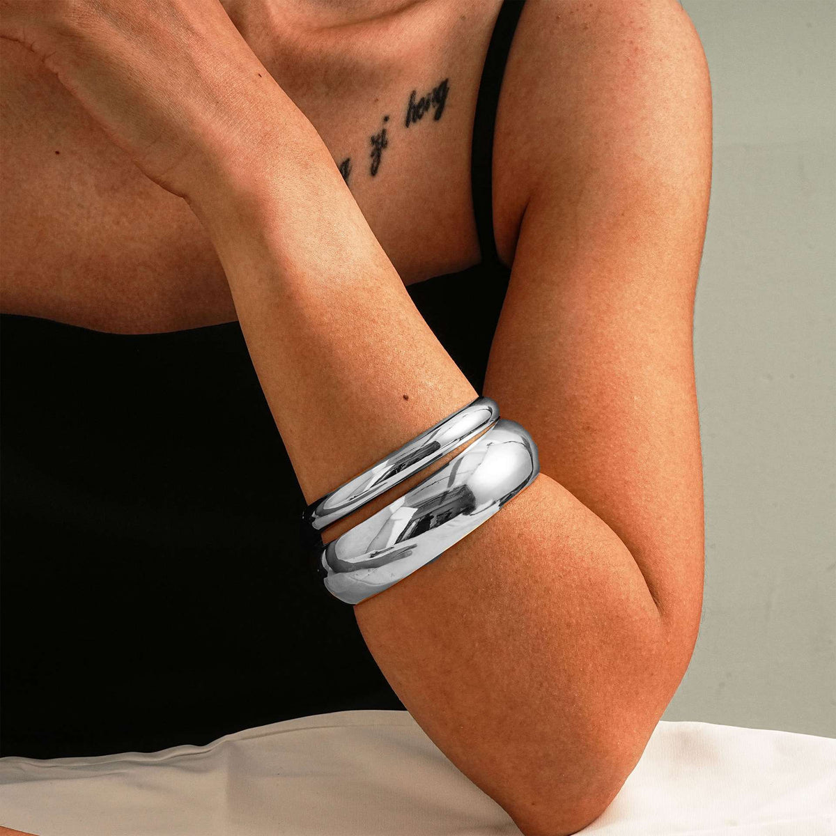 Silver bracelet on a person's wrist with a neutral background