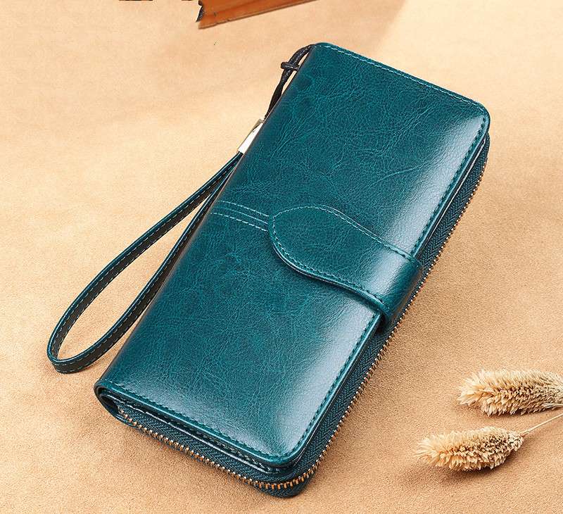 Teal wallet with a strap on a beige background