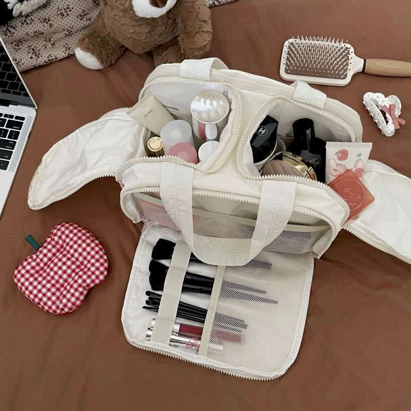 Open beige travel bag with makeup and grooming items on a brown surface.