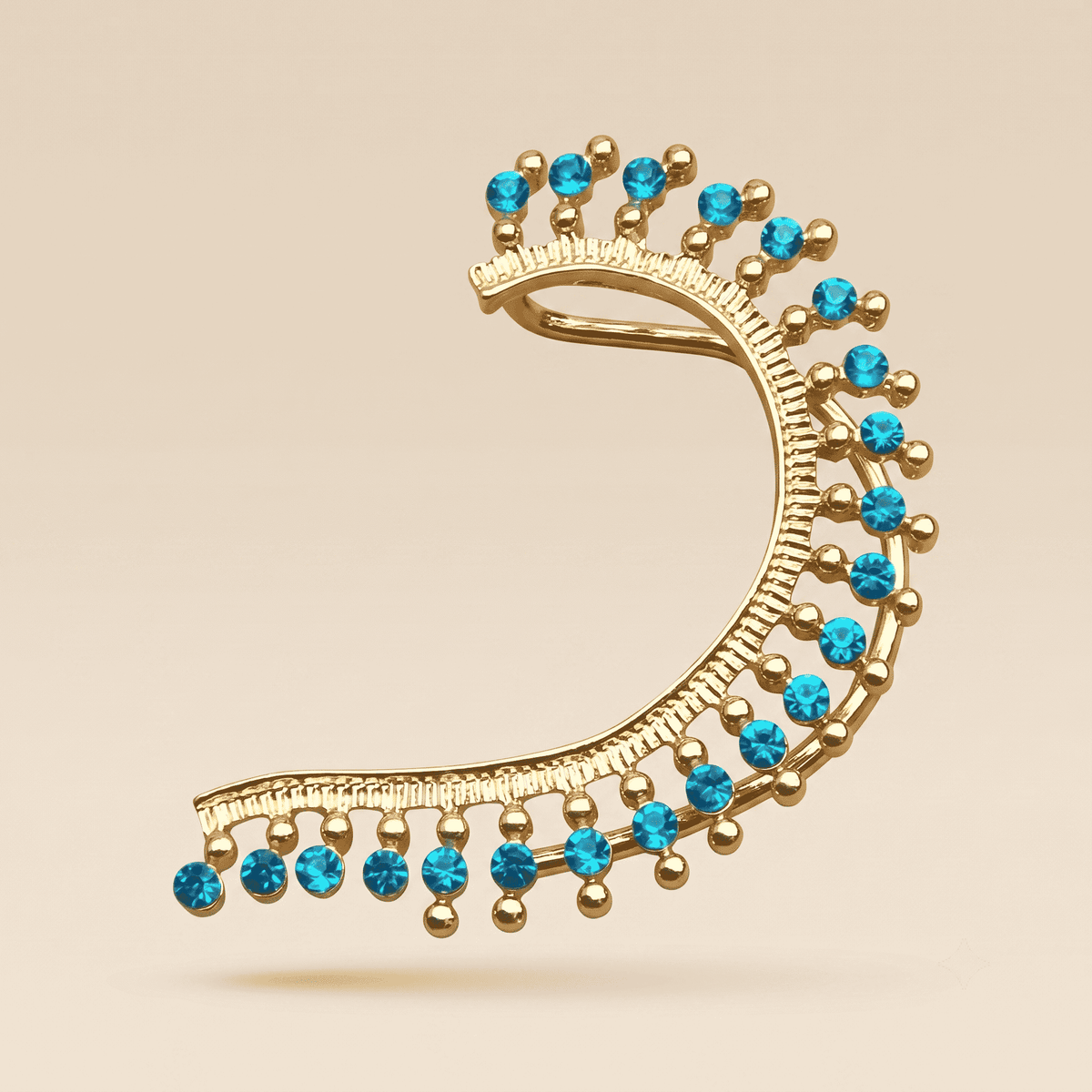 Gold crescent-shaped earring adorned with small round blue gemstones and gold beads, shown on a plain beige background.