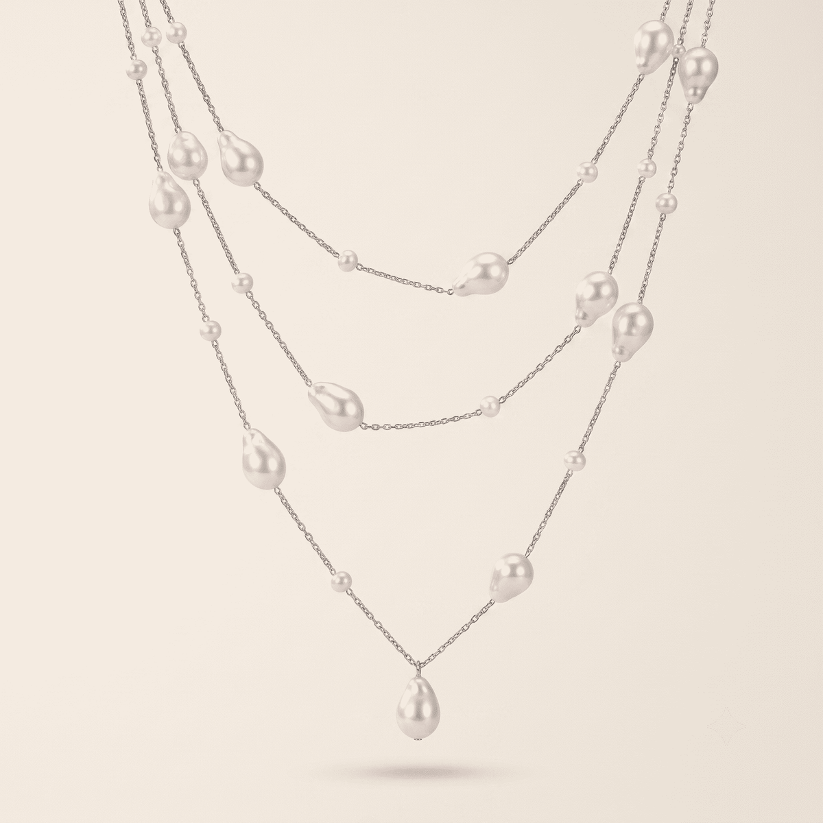 A multi-strand silver necklace featuring irregular white baroque pearls of varying sizes, displayed against a solid light beige background.