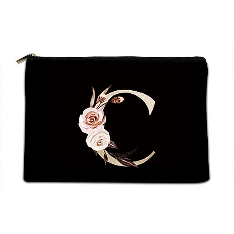 A black zippered pouch featuring a decorative embroidered letter 'C' embellished with pink and white roses, set against a plain white background.