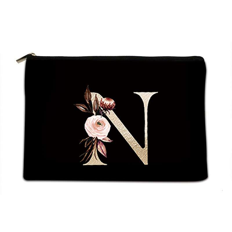A black zippered cosmetic pouch featuring a large decorative letter 'N' embellished with a pink rose and floral accents, set against a plain white background.