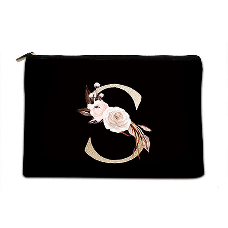A black zippered pouch featuring a large decorative letter 'S' design embellished with cream and pink flowers, brown leaves, and gold glitter accents, set against a plain white background.