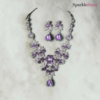 Purple jewelry set with necklace and earrings on a light gray background, branded 'SparkleSway'.