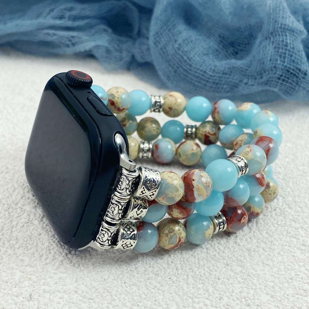 Beaded bracelet with a watch on a textured surface