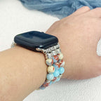 Person wearing a smartwatch with multiple bracelets on a light background