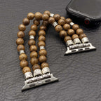 Wooden beaded bracelet with silver skull charms on a textured surface