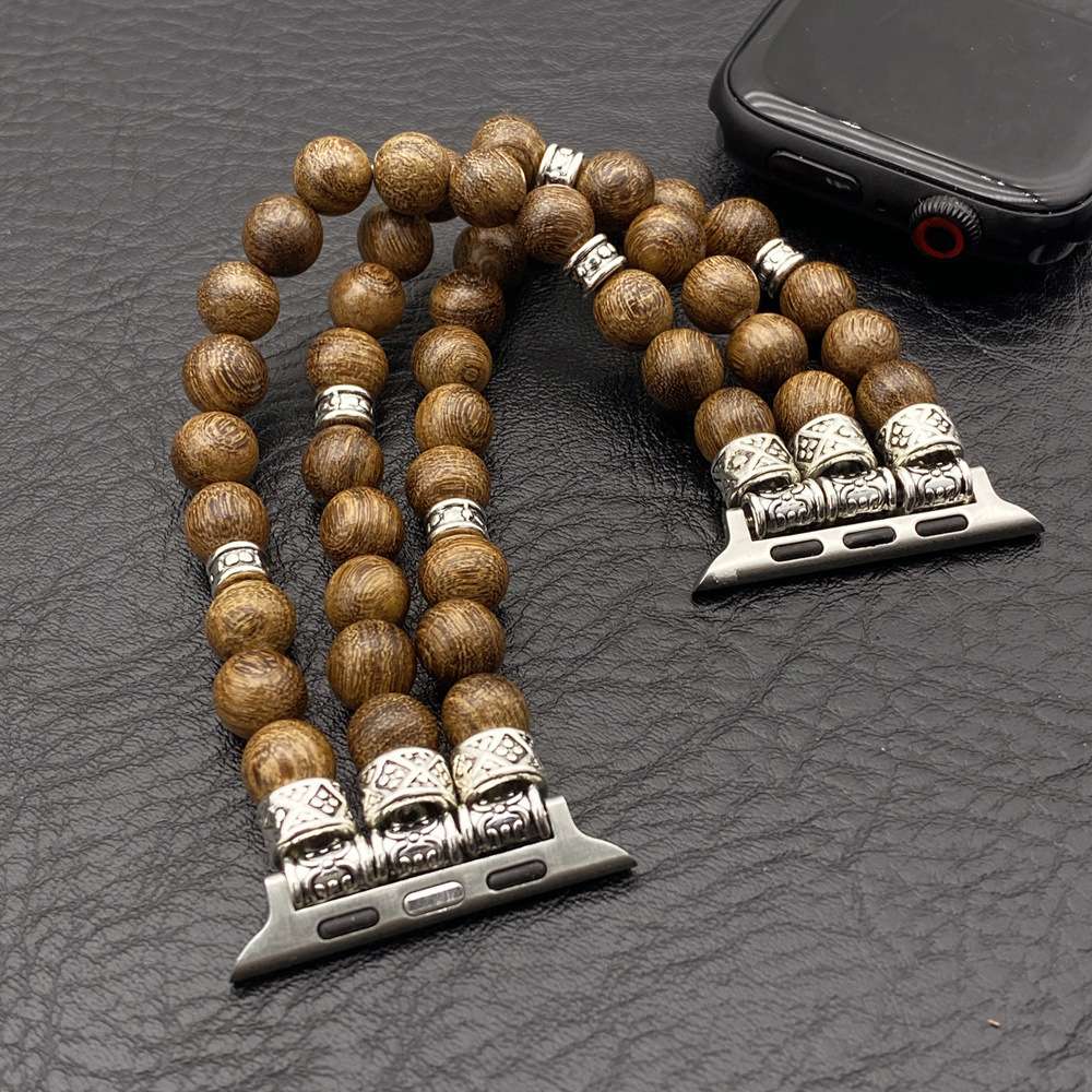 Wooden beaded bracelet with silver skull charms on a textured surface