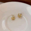 A pair of gold crescent-shaped hoop earrings resting on a white ceramic plate.