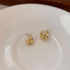 A pair of gold crescent-shaped hoop earrings resting on a white ceramic plate.