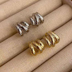 Gold and silver spiral earrings on a beige fabric background