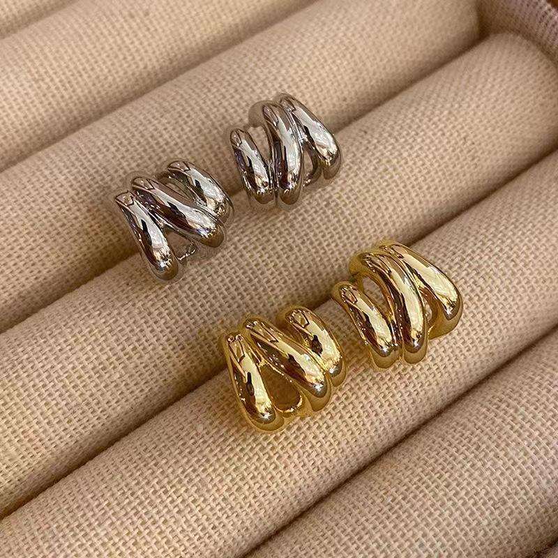 Gold and silver spiral earrings on a beige fabric background