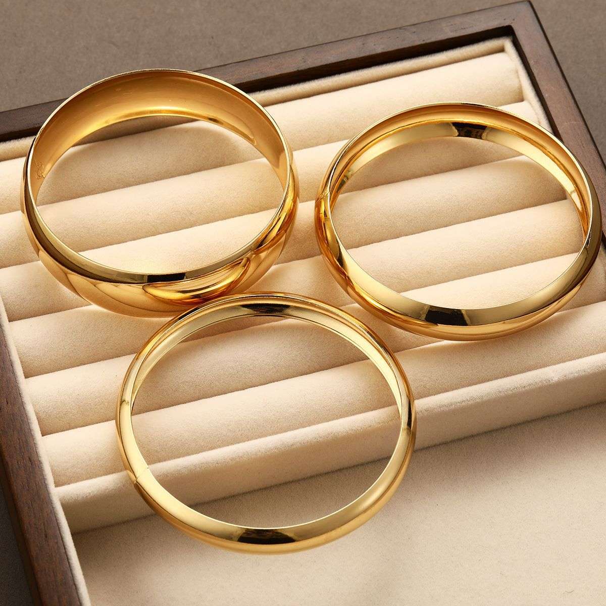 Three gold rings on a beige jewelry display box